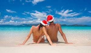 couple with merry christmas hats on romantic tropical beach for summer holiday